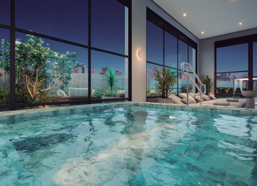 Piscina coberta com vidros de pé-direito duplo e vista noturna da cidade