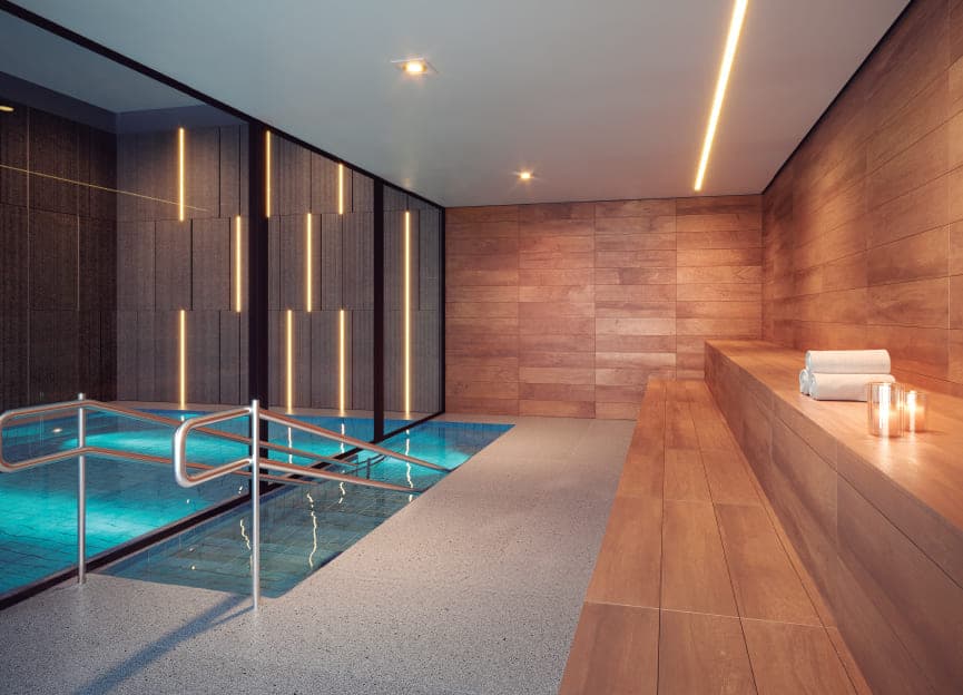 Piscina de imersão interna revestida em madeira, com corrimão, banco lateral e toalhas